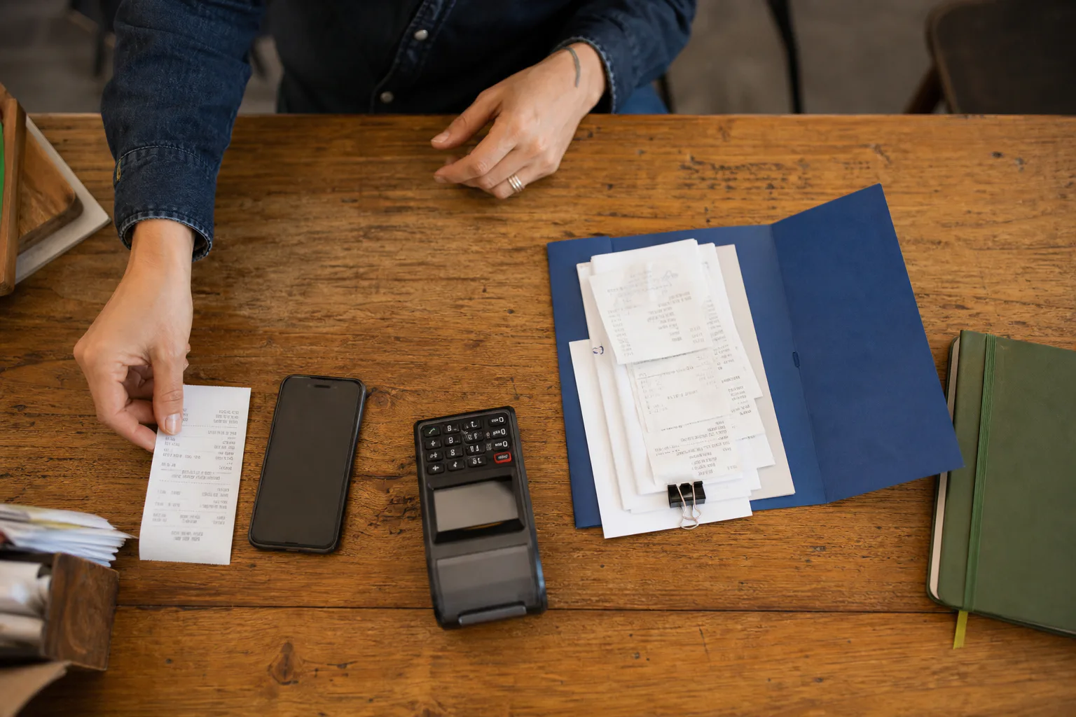 Bon, Smartphone, Kartenterminal und geordnete Belege auf einem Arbeitstisch
